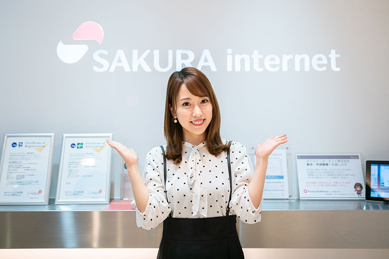 さくらインターネットのロゴ前で写真を撮る福原香織さん