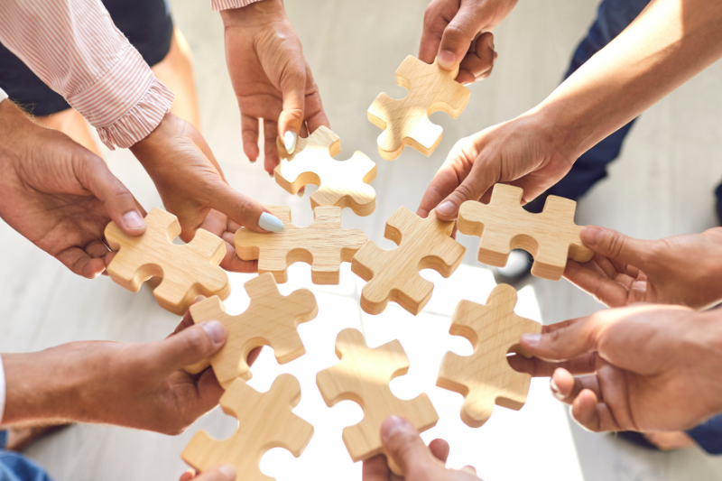 パズルのピースを持つ大勢の手の写真